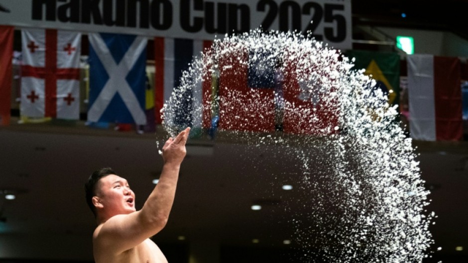 Sumo wrestlers throw salt on the dohyo to drive away evil spirits
