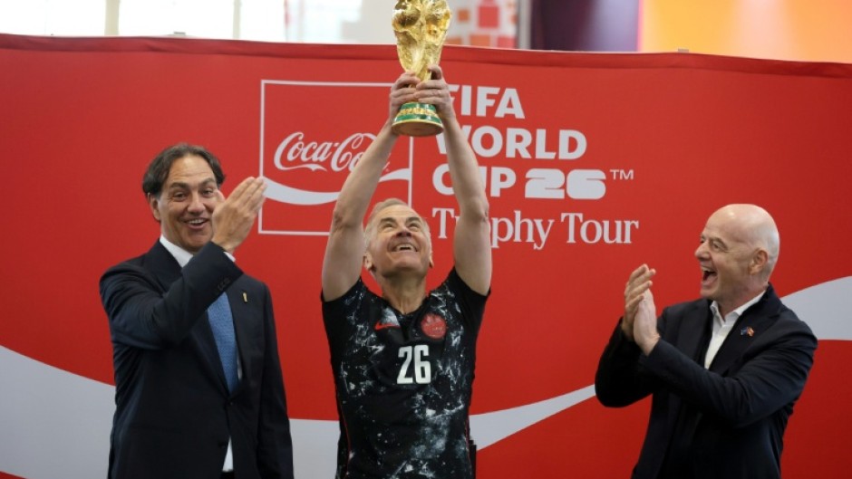 Canada's Prime Minister Mark Carney holds aloft the World Cup trophy next to FIFA President Gianni Infantino in May