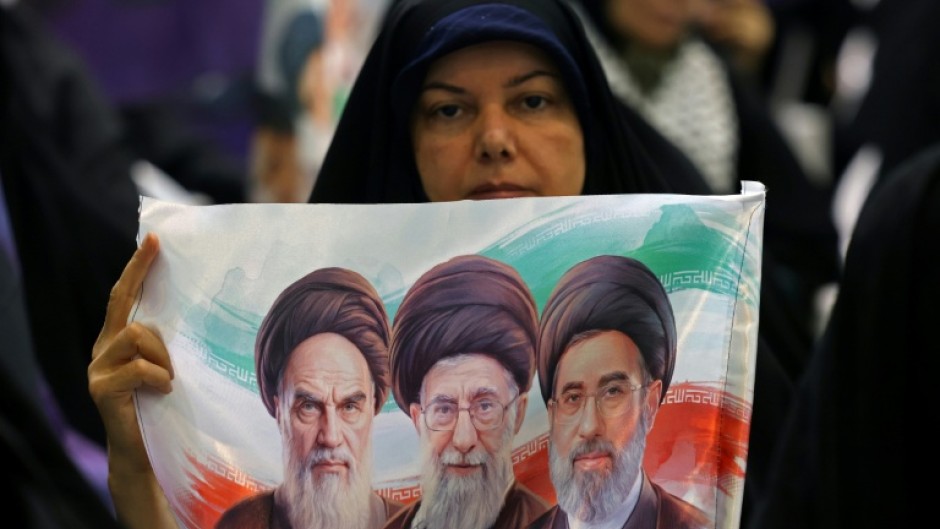 An Iranian woman holds an image of the former and current Iranian supreme leaders in Tehran
