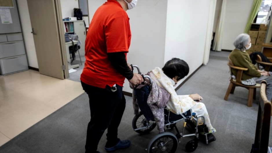 A caretaker wheels an elderly woman after a bath at a day care facility for senior citizens in Tokyo