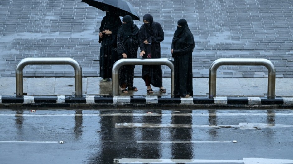 Women wait for a taxi in rainfall in Mumbai on June 23