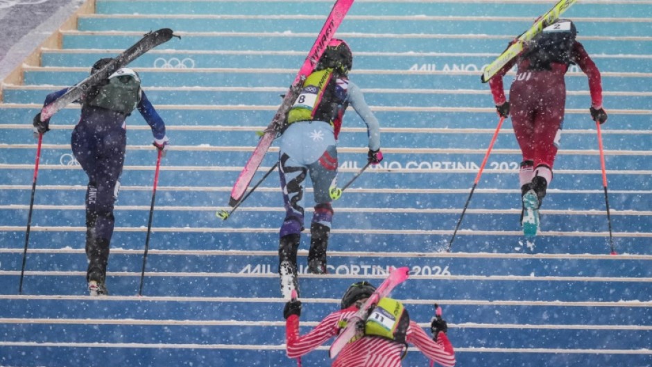 Competitors race uphill in a women's sprint ski mountaineering heat during the Milano Cortina 2026 Winter Olympic Games