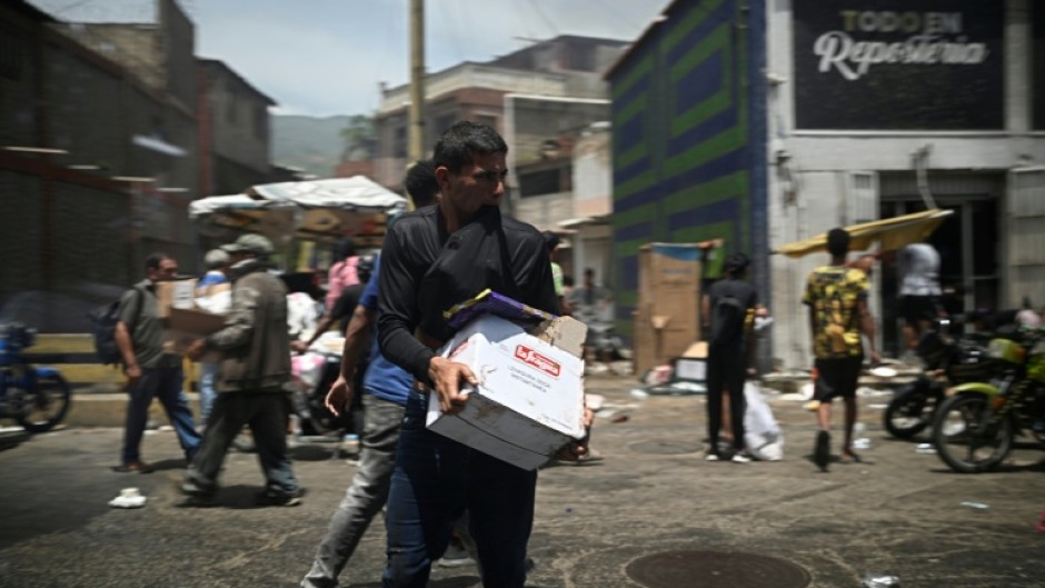 A man carries a box as looting erupted in Catia La Mar in La Guaira State, about 30 km northwest of Caracas, on June 25, 2026