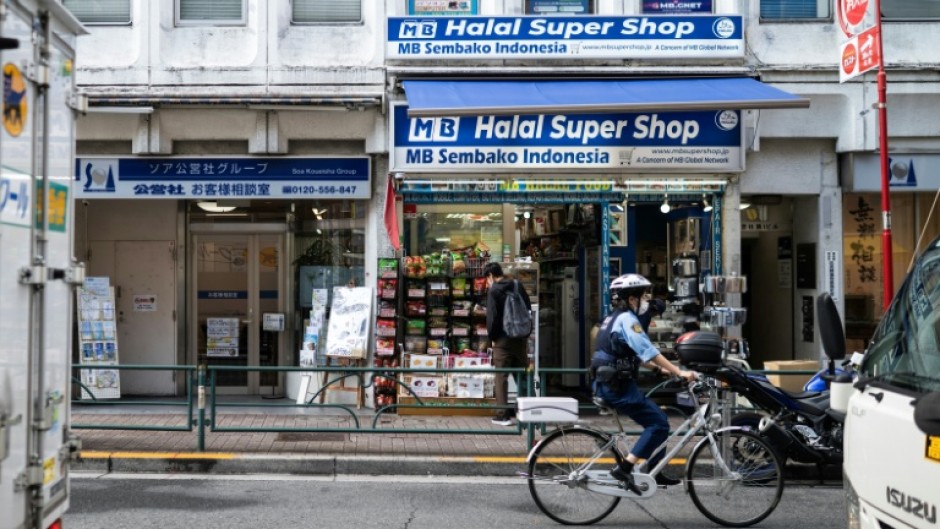 A police officer bikes past a convenience store in the Okubo–Shin area in Tokyo, a neighbourhood known for its large immigrant communities