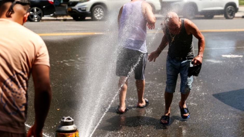 Men cool off at a fire hydrant in the Hamilton Heights neighborhood in Manhattan