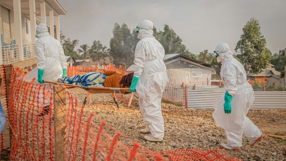Healthcare workers carry a patient suffering from Ebola at a treatment centre in Bunia