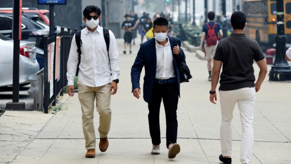 People wear face masks while walking through downtown Chicago as smoke from wildfires burning in Canada blankets the Chicago metropolitan area on July 16, 2026