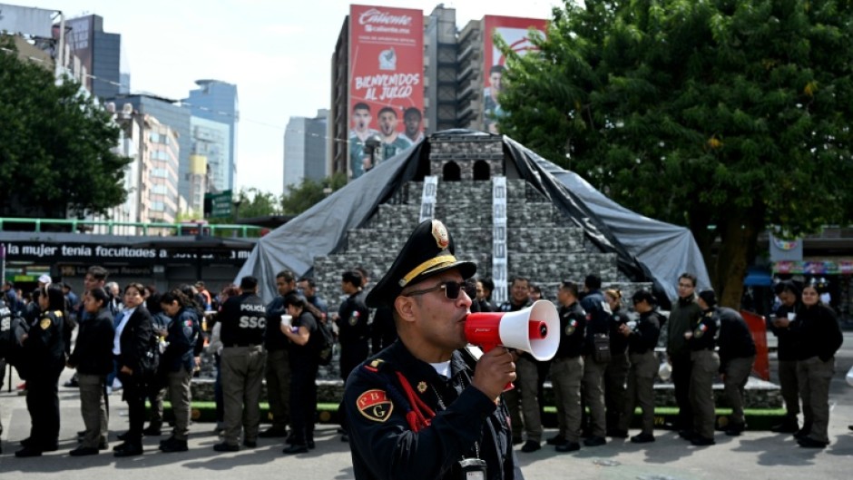 A member of the Secretariat of Citizen Security uses a megaphone to give instructions to personnel evacuated from several buildings following a preventive evacuation in Mexico City