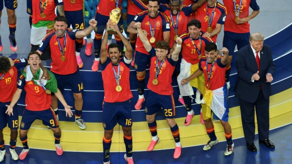 Spain's midfielder #16 Rodri (front C) lifts the trophy with Spain's players next to US President Donald Trump (R) during the final ceremony after the 2026 World Cup
