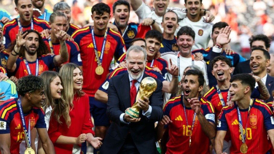 Spain's King Felipe VI (C) lifts the trophy next to Princess Leonor (2nd-L) and Princess Sofia (3rd-L) after winning the 2026 World Cup football tournament final match between Spain and Argentina at East Rutherford