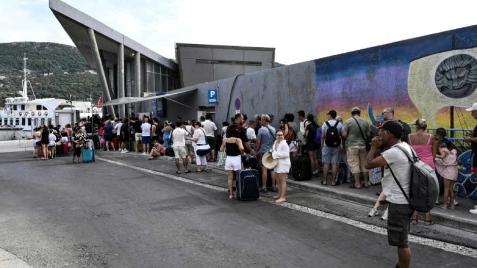 Visiting Turkish tourists line up to get their visa on arrival at the customs office in the village of Vathy on Greece's Samos island