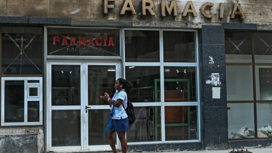 A woman walks past a pharmacy in Havana, where Cuba's communist authorities have announced an opening of sectors of its economy such as petrol stations, medicine sales and electricity generation to the private sector