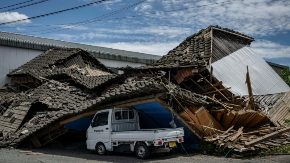 A house is seen collapsed onto a car in Yatsushiro, Kumamoto prefecture