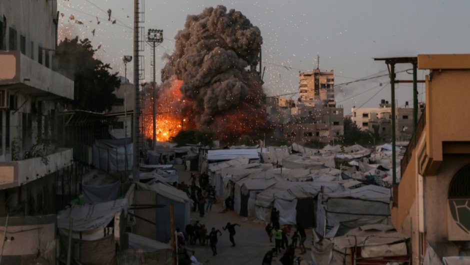 Palestinians run for cover as smoke and fire rise during an Israeli strike on the the Al-Muttaqin Mosque in Gaza City on July 28, 2026