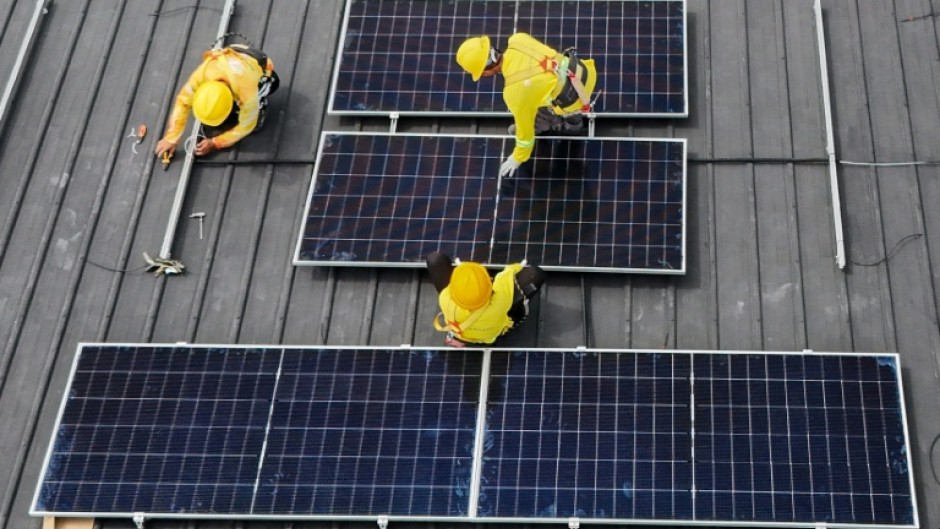 Workers instal solar panels on a roof in Carmona, in the Philippine province of Cavite