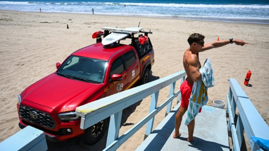 Los Angeles County lifeguard Maximus Oberto gestures as he monitors swimmers in the Pacific Ocean in Manhattan Beach
