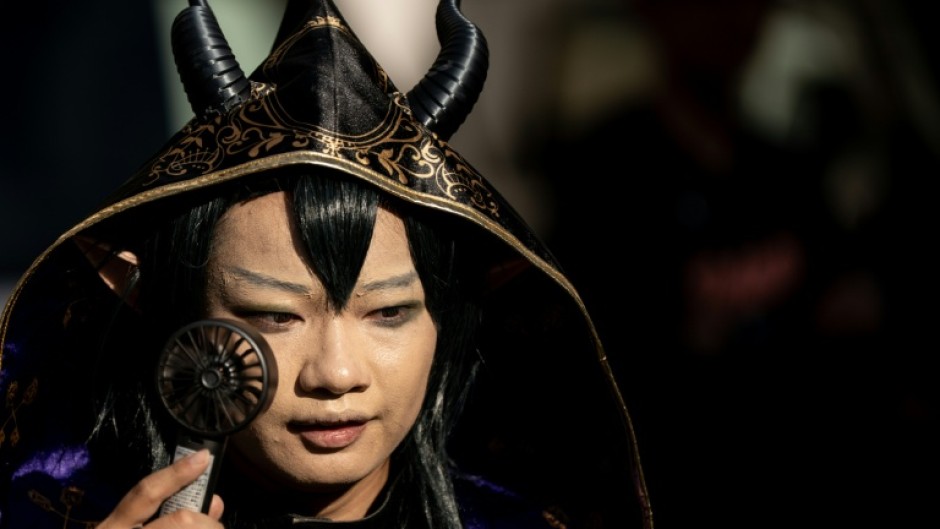 A cosplayer uses a portable fan to cool down while visiting the Osu Shopping Street before the Osu Cosplay Parade, during the second day of the World Cosplay Summit 2026 in Nagoya on August 1, 2026.