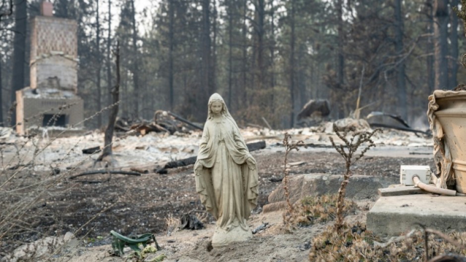 A Virgin Mary statue remains untouched in front of a burned out residential home in the Balboa neighborhood of Spokane, Washington, on August 2, 2026.