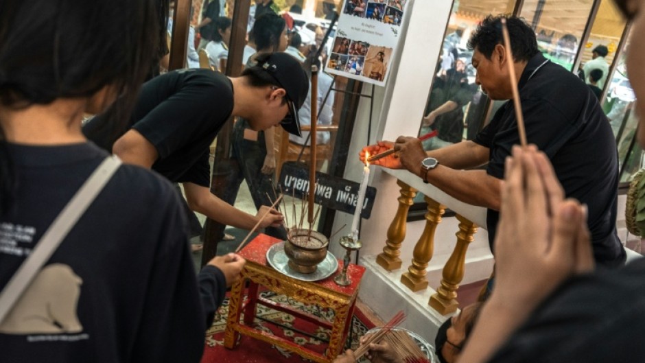Dozens of bereaved students, parents and teachers queued at a Buddhist temple in Thailand to pray over the body of a 12-year-old girl, one of eight victims of a home and school shooting.