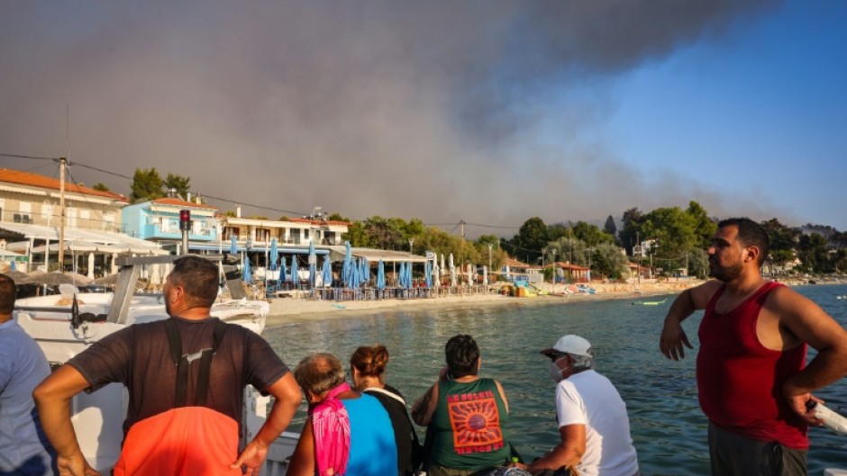People use small boats to flee a wildfire near the village of Siviri, northern Greece