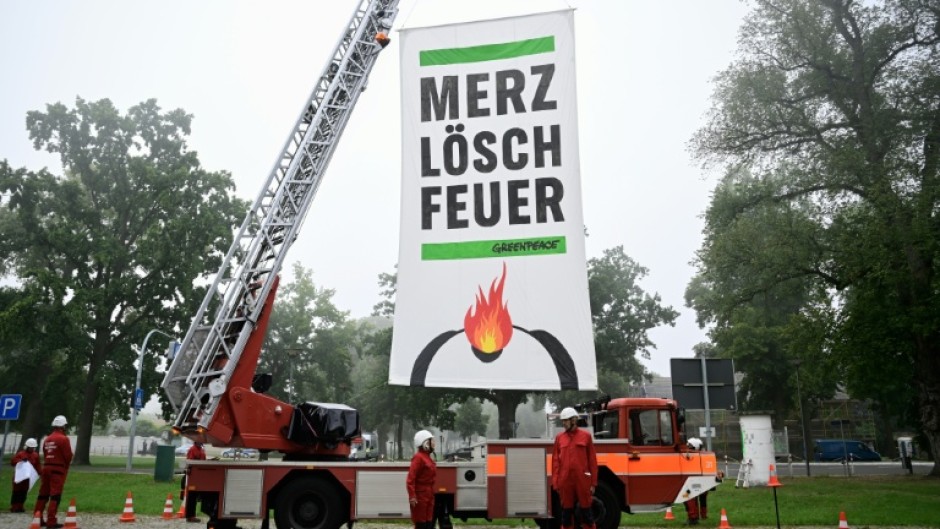 Greenpeace activists near the cabinet retreat set up a fire engine with a banner demanding: 'Merz, extinguish the fire'