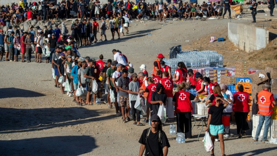 Red Cross volunteers distribute food to migrants who remain living on the streets of Ceuta