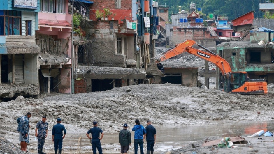 Workers use excavators to clear the mud at the Dhunge Bazaar in Nepal's Nuwakot district on August 29, 2026