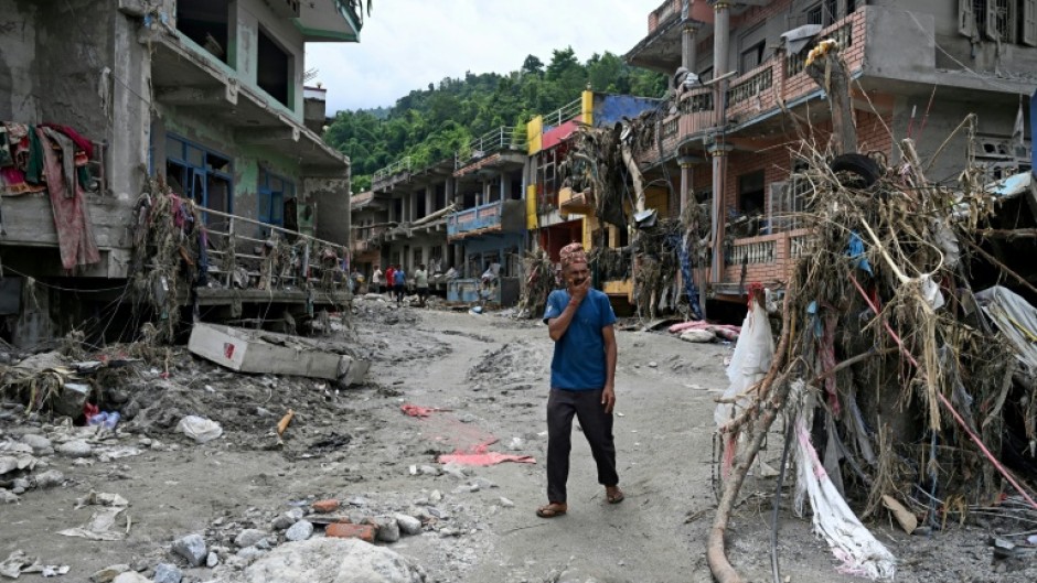 A man walks past damaged houses following flash floods at Devighat in Nepal's Nuwakot district on August 31, 2026
