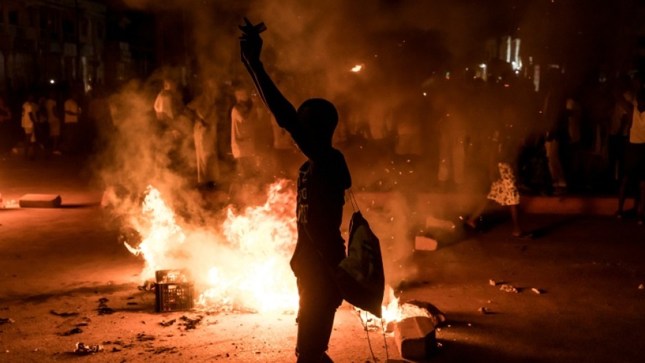 A demonstrator stands next to a burning barricade during a protest over The Gambia's electricity crisis