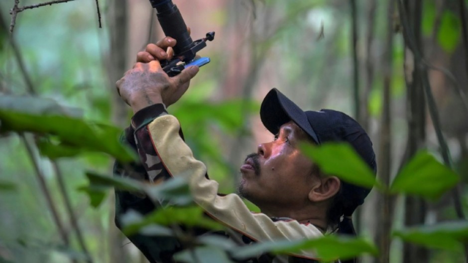 Wildlife observer and former poacher Octavius using a mobile phone equipped with a telephoto lens to take pictures of wildlife in a forest near Labian village in Kapuas Hulu, West Kalimantan