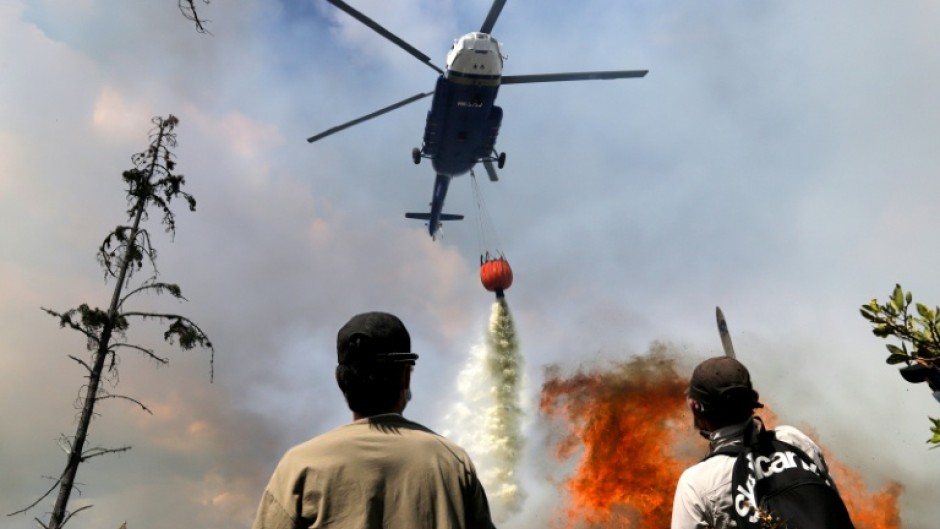 A helicopter drops water on a forest fire in central Colombia