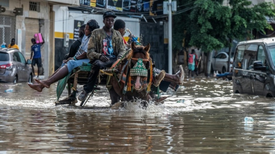 A horse cart transports passengers through a flooded street in Dakar, on October 5, 2026