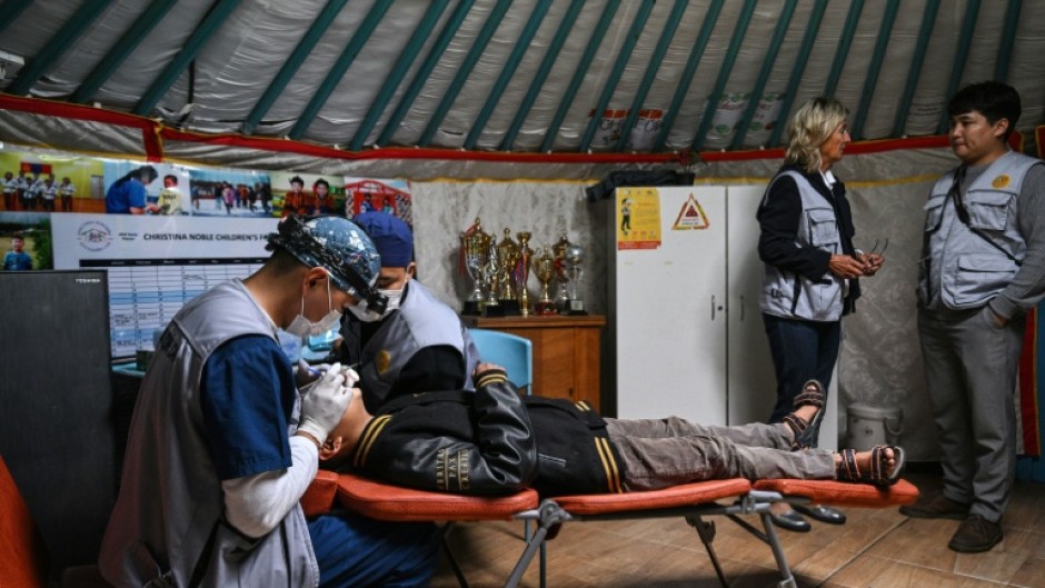 A dentist checks a child's teeth at a mobile dental clinic inside a traditional Mongolian ger in Ulaanbaatar