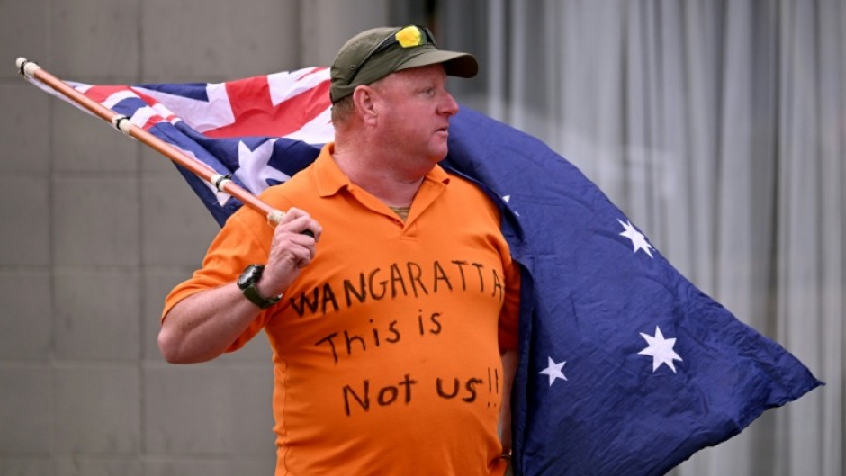 A man holds an Australian flag outside the office of Australian politician Helen Haines on October 20, 2026. The independent lawmaker Haines underwent surgery after an attack
