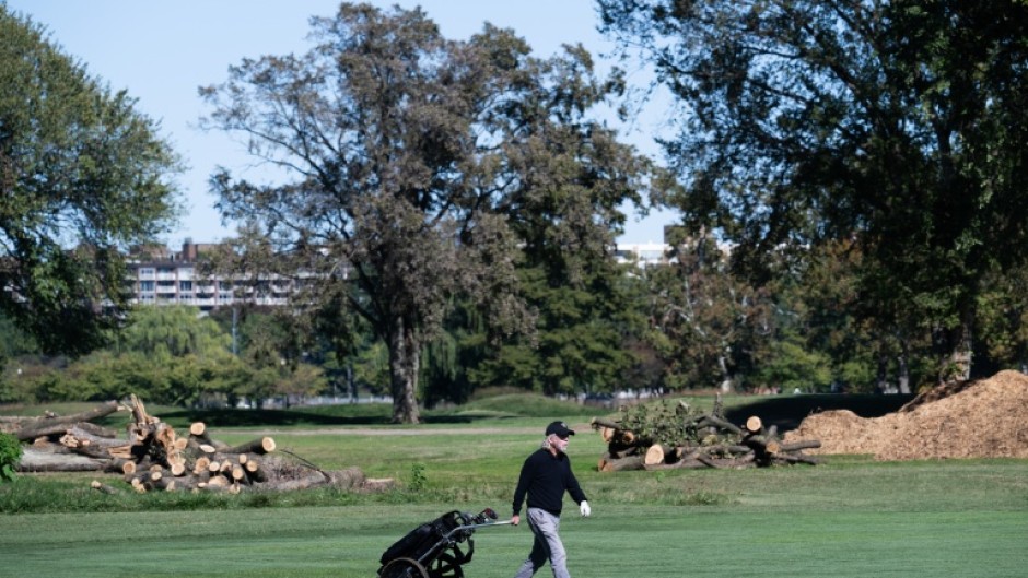 A golfer walks on the course in front of cut down trees at East Potomac Golf Links in Washington DC