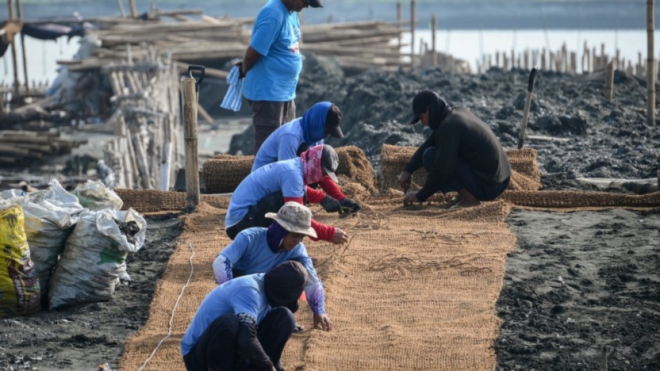 Workers lay coconut-fibre bags next to oyster shells on a breakwater at Pamarawan Island in Malolos City, in the Philippines Bulacan province