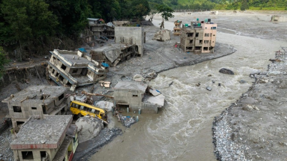 A torrent of muddy water surges past houses in the aftermath of flash floods in Nepal's Nuwakot district on August 29, 2026