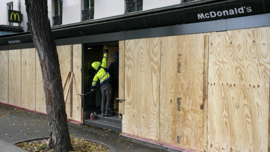 A worker tends to the boarded-up facade of a ransacked McDonald's outlet
