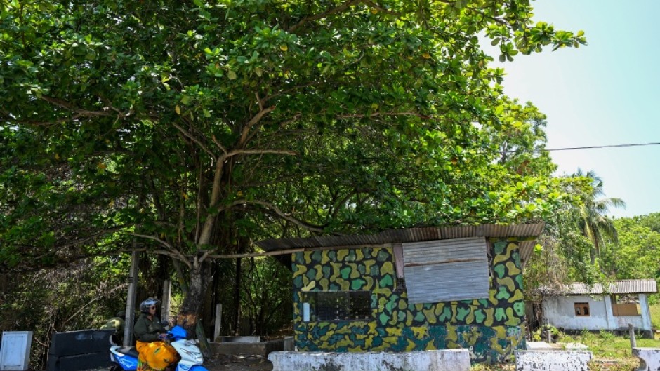 A woman rides a scooter past an uninhabited army settlement on a disputed land at Batticaloa in Sri Lanka's Eastern Province