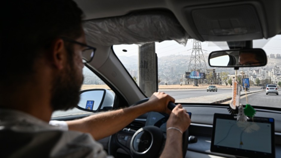 Ahmed Al-Lahham, a driver for ride-hailing application "Yalla Go!", drives his plug-in hybrid vehicle (PHEV) in Damascus