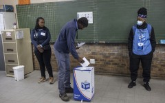 A voter casts his ballot as IEC officials look on. AFP/Michele Spatari