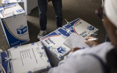 An election observer writes down notes as an IEC official tapes ballot boxes shut. AFP/Emmanuel Croset