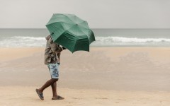 File: A beachgoer uses an umbrella to protect himself against the rain in Durban. AFP/Rajesh Jantilal