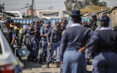 South African Police Service (SAPS) officers walk during raid to retrieve looted goods during a protest at Diepkloof Hostel in Soweto on May 19, 2025. 