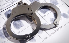 File: Handcuffs laying on top of fingerprint chart. GettyImages/TheCrimsonRibbon