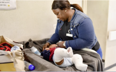 Baby with two casts on their legs being attended by a nurse