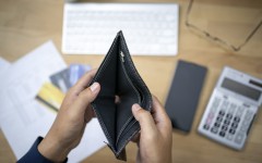 File: A person looking at an empty wallet with a calculator and credit cards. GettyImages/seksan Mongkhonkhamsao