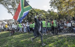 A “March and March” supporter waves the South African flag during a protest march in Durban on May 20, 2026.