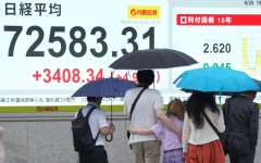 Pedestrians walk past an electronic quotation board displaying the Nikkei Stock Average. AFP/Kazuhiro Nogi