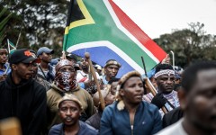 Members of the Zulu regiment known as the ‘Amabutho’ hold a South African flag as they march during a demonstration by the "March and March" movement. AFP/Marco Longari